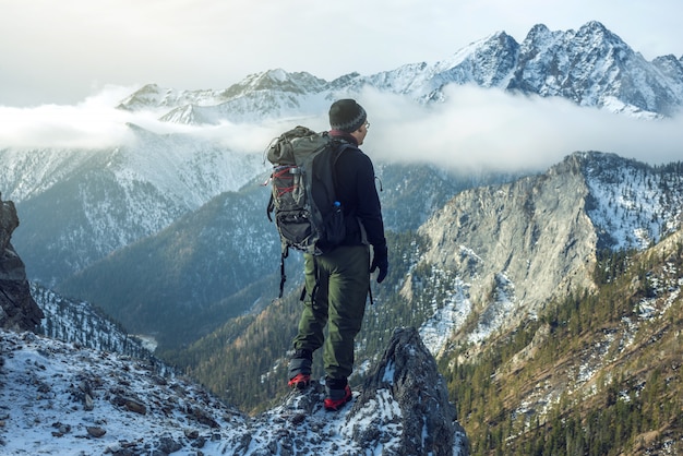 Man with a backpack standing on top of the mountain