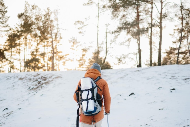 Man with backpack trekking in mountains Cold weather snow on hills Winter hikingxA