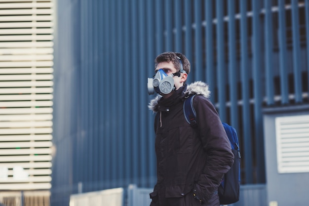 Man with backpack wearing industrial mask in city. Coronavirus protection