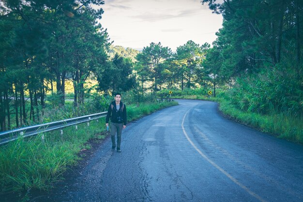 Man with Backpacks in casual Travel Clothes walking along road in mountains.