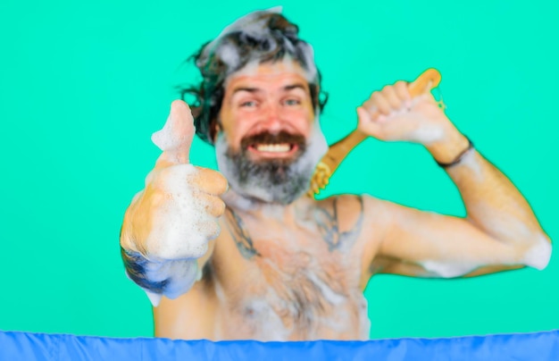 Man with bath brush washing body shows thumb up bearded guy taking shower showing sign ok