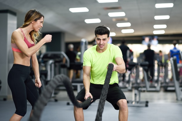 Man with battle ropes exercise in the fitness gym.