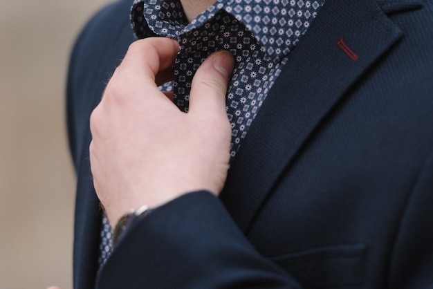 A man with a beard in a blue suit poses on the street to advertise men's clothing. 