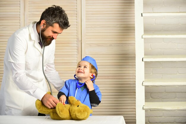 Man with beard and boy hold stethoscope on wooden background