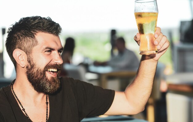 Photo man with beard drink beer man holding mug of beer guy at the bar counter hipster relaxing at pub han