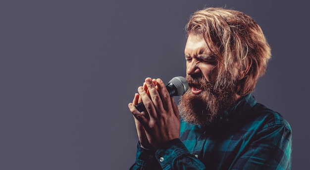 Man with a beard holding a microphone and singing Bearded man in karaoke sings a song into a microphone