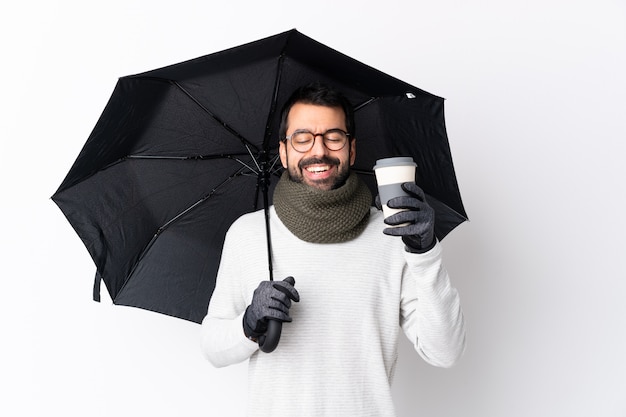 Man with beard holding umbrella over isolated wall