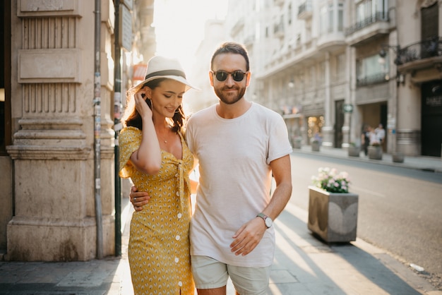 A man with a beard is hugging around the waist with his hand of a girlfriend in a hat and a yellow dress