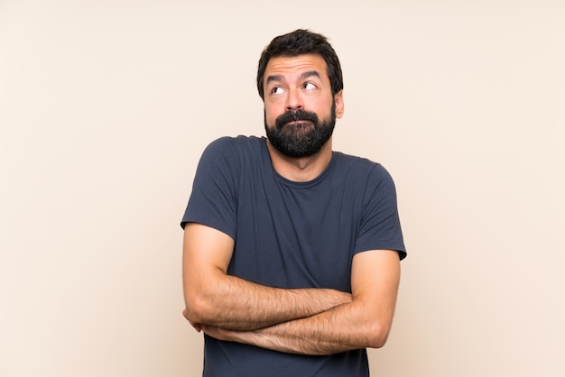 Man with beard making doubts gesture while lifting the shoulders