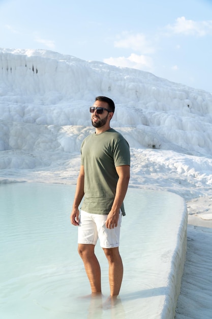 Man with beard and sunglasses posing with his feet sunk in the water of the thermal pools in pamukkale