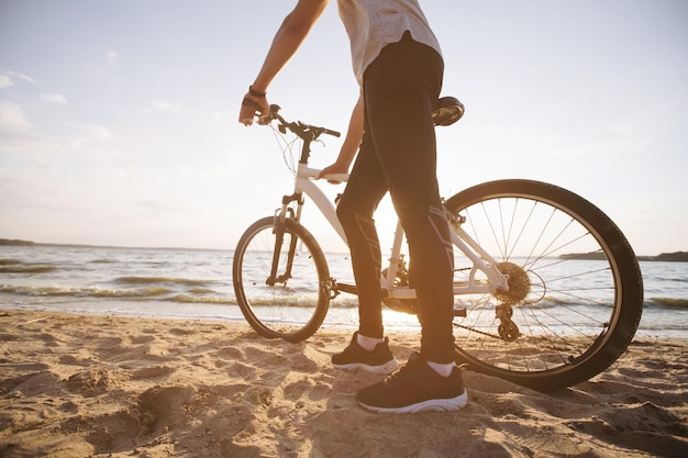 Man with a bicycle standing on a sandy beach