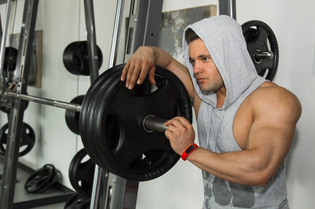 A man with big muscles is engaged in weightlifting in the gym. A pumped-up athlete goes in for sports on heavy weight simulators. sport exercises.