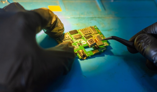 man with black rubber glove repairing mobile phone