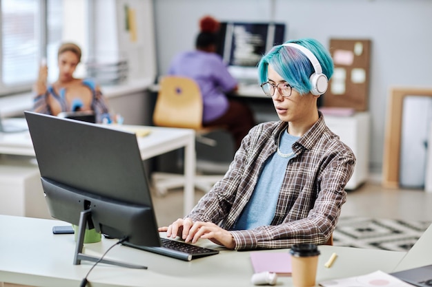 Man with blue hair using computer in office