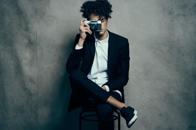 Man with camera indoors on fabric background tshirt model curls