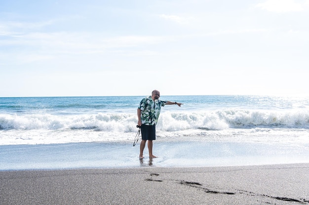 Man with a camera pointing ahead on the beach