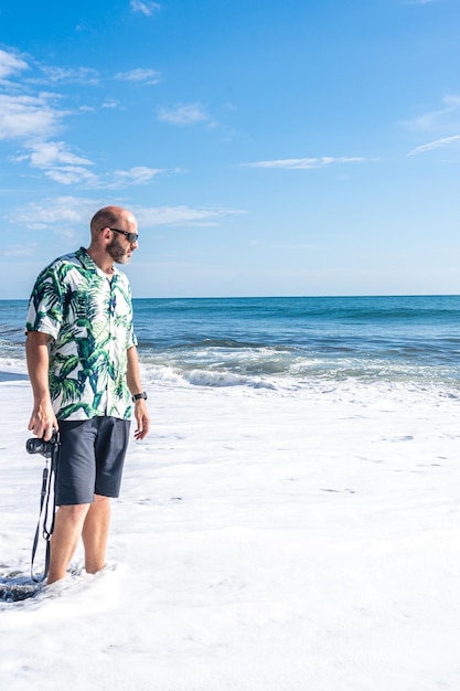 Man with a camera walking along the beach