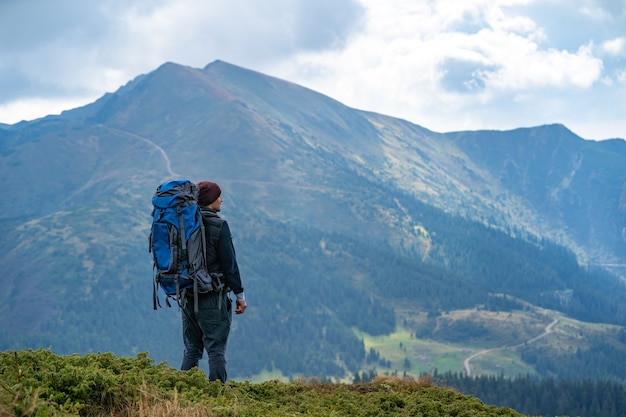 The man with a camping backpack standing on the mountain