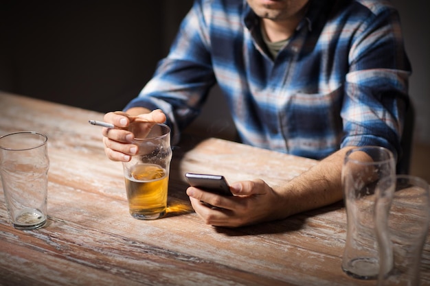 man with cellphone drinking alcohol and smoking