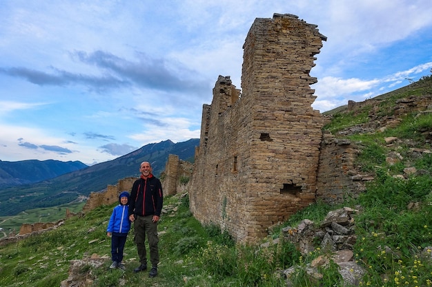 A man with a child at the medieval defensive towers in the ancient village of Goor Russia Dagestan 2021