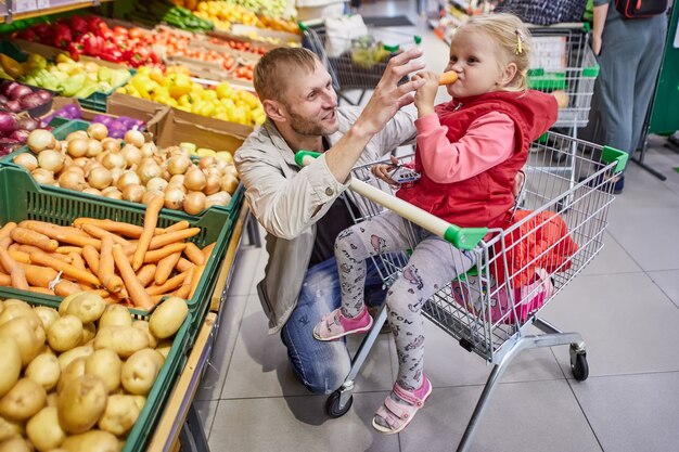 Man with child in shopping cart in grocery store