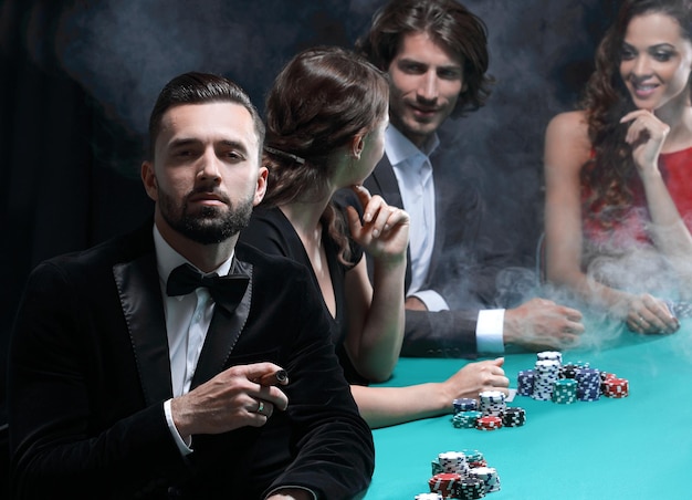 Man with cigar looking up from poker game in casino