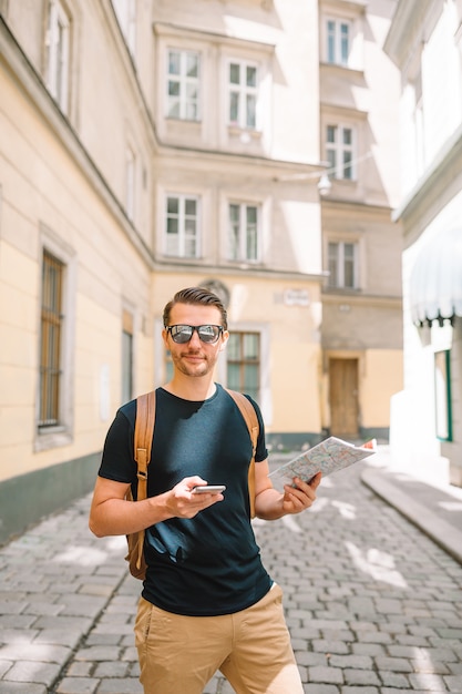 Man with a city map and backpack in European street.