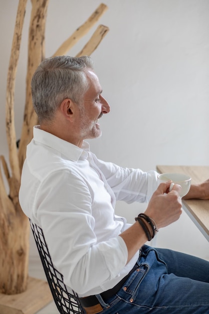 Man with coffee sitting sideways to camera