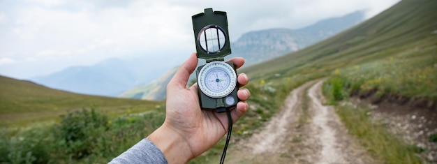 Man with compass in hand on mountains road