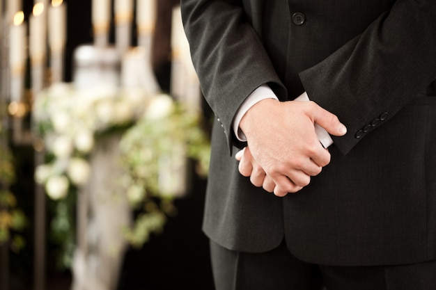 Man with crossed hands at funeral