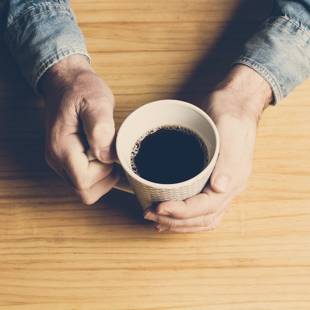 A man with a cup of coffe on a table