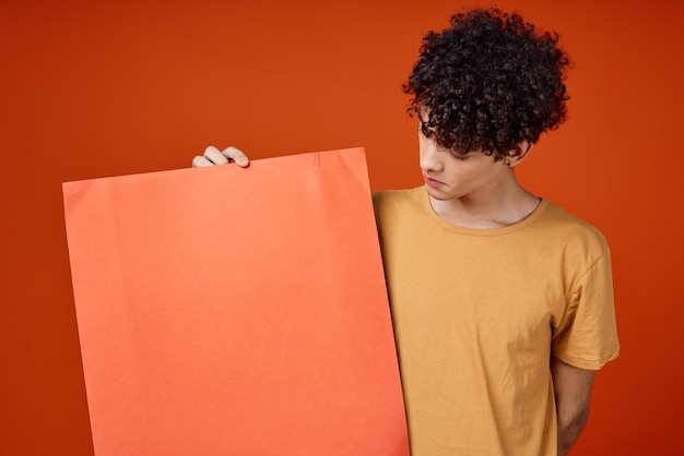 Man with curly hair holding a poster in hands Copy Space cropped view