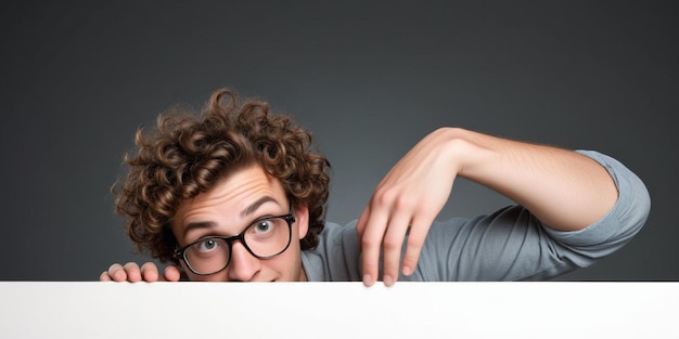 Photo a man with curly hair looks over a wall with his finger pointing up