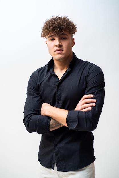 A man with curly hair stands in front of a white background.