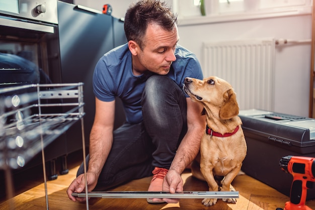 Man with dog building kitchen cabinets