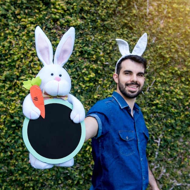 Man with Easter bunny ears holding Easter bunny selective focus