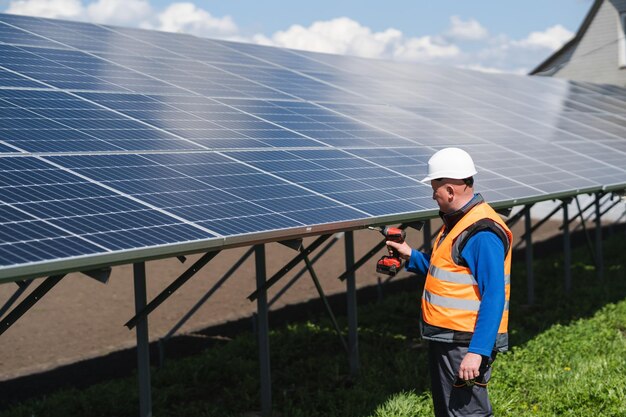 Man with electric wrench tightens the bolts securing solar panels to a metal base