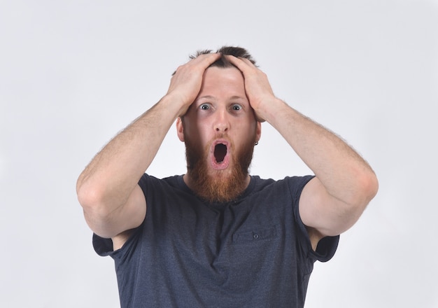 Man with expression of forgetfulness or surprise over white wall