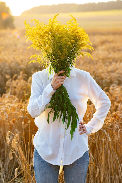 A man with a face hidden behind a bouquet of flowers in a field depersonalization Soft focus