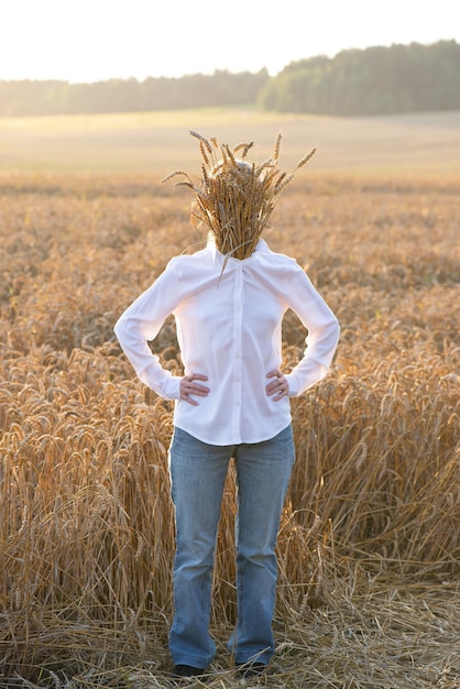 A man with a face hidden behind spikelets of wheat in a field with sunlight depersonalization