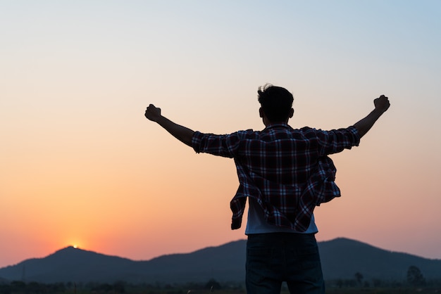 Man with fist in the air during sunset, Feeling motivated, freedom concept.