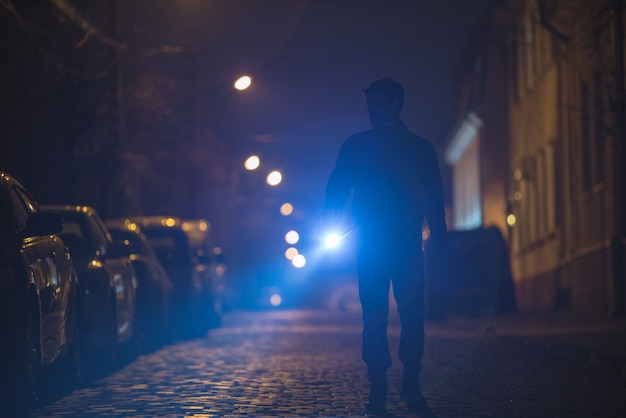 The man with a flashlight inspect the street. Evening night time