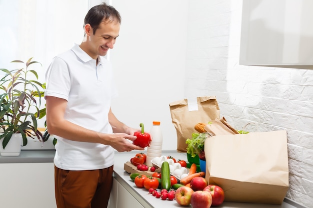 Man with fresh products at table indoors, closeup. Food delivery service