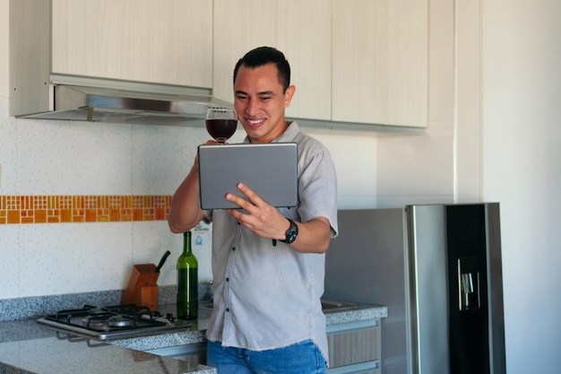 Man with a glass of wine having a video call with a tablet at home