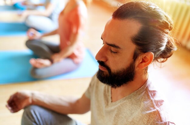 Photo man with group of people meditating at yoga studio