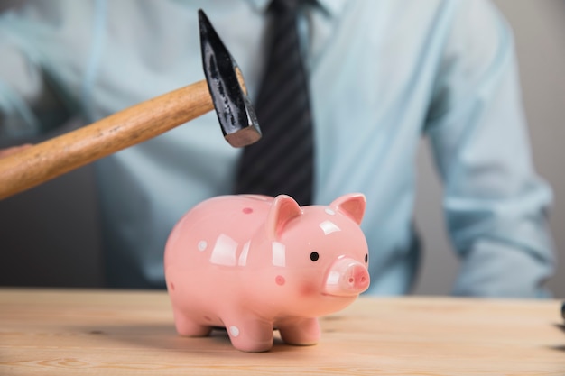 A man with a hammer breaks a piggy bank