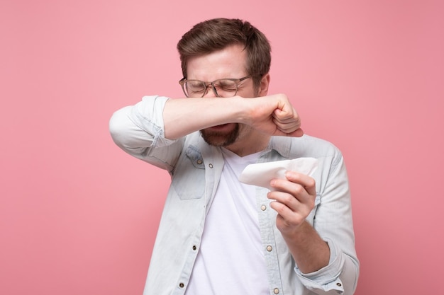 Man with handkerchief and glasses sneezing being ill or having allergy