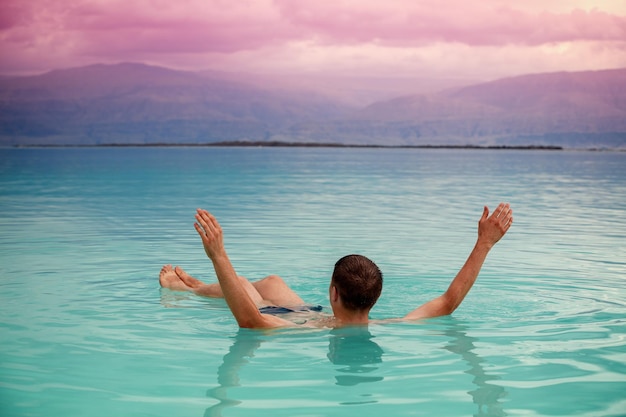 Man with hands in the air swimming in the Dead Sea Spa procedures