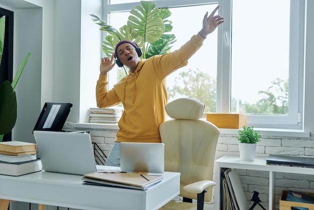 Photo a man with headphones on and a keyboard in front of a window