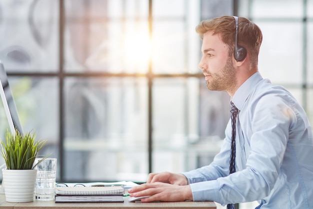 Man with headphones and laptop working in office